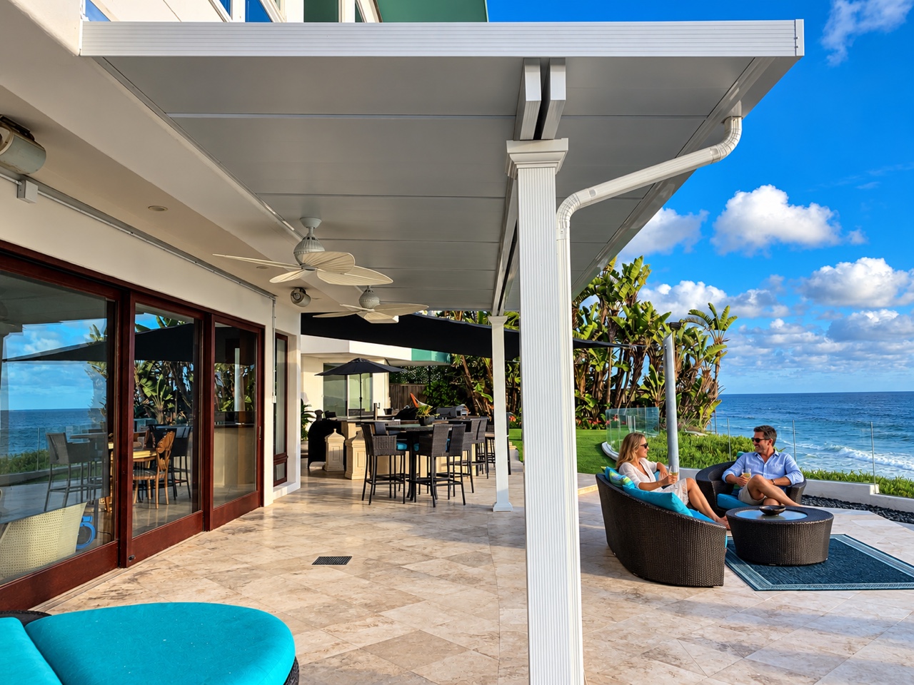 A couple enjoying an oceanfront patio beneath a solid roof cover